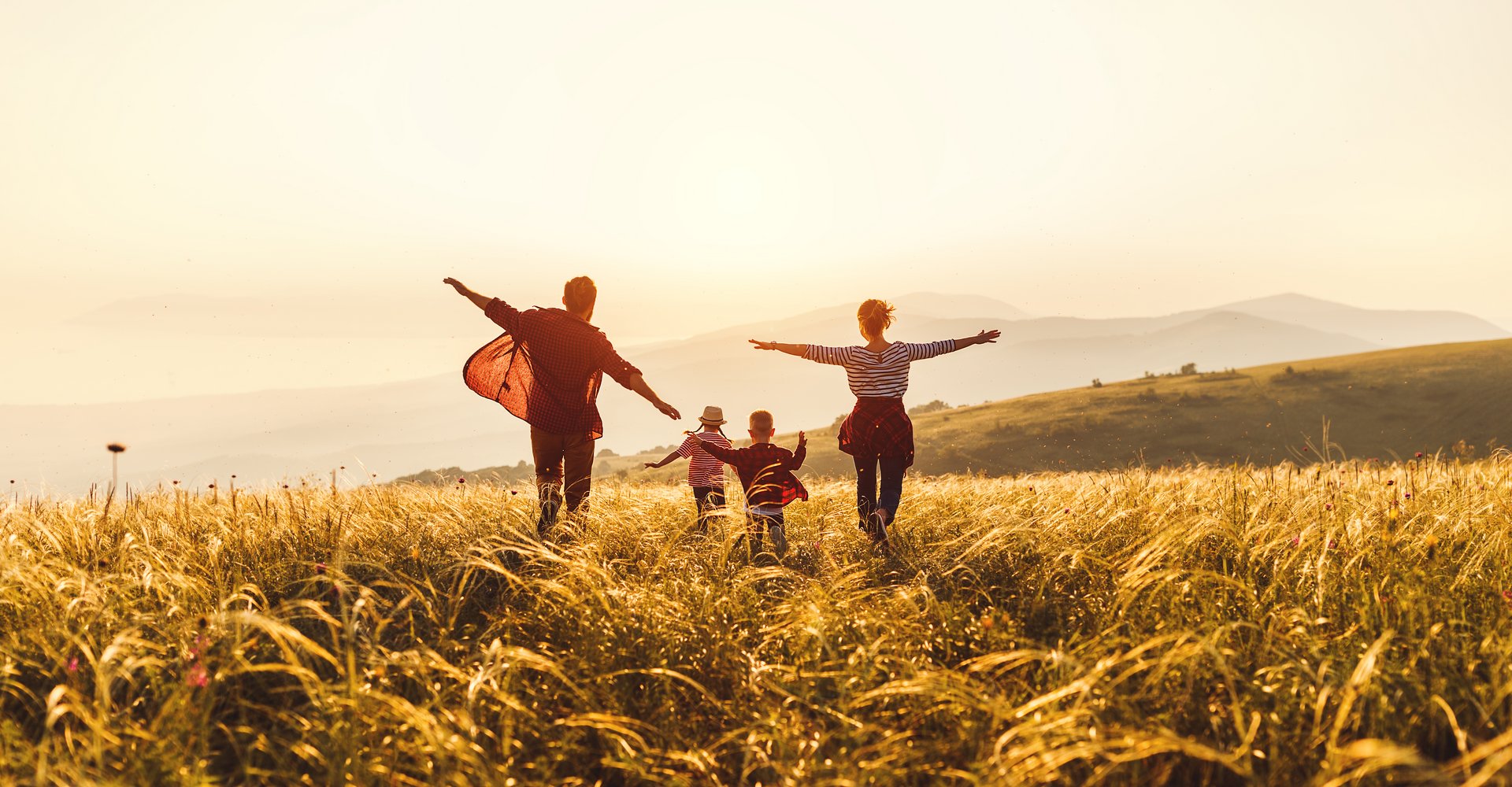 Glückliche Familie: Mutter, Vater, Kinder Sohn und Tochter laufen und springen bei Sonnenuntergang.